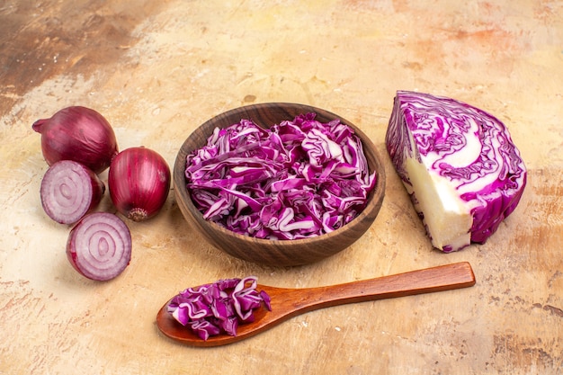 Top view a bowl of chopped red cabbage and several red onions for vegetable salad on a wooden background with copy place