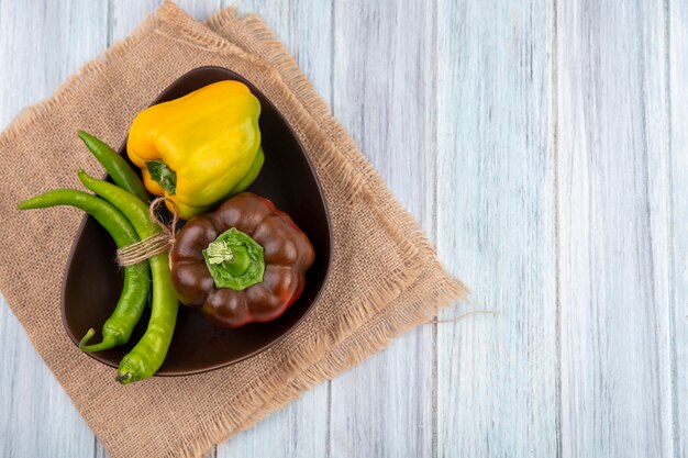 Top view of bowl of pepper on sackcloth on wood with copy space