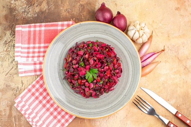 Top view of bowl of a red salad with greens on it on a wooden backgorund