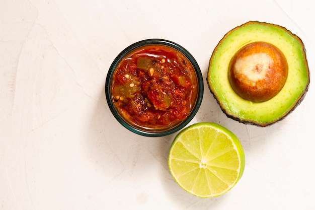 Top view bowl of sauce near avocado and lime