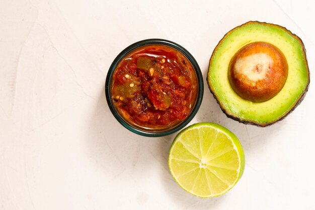 Top view bowl of sauce near avocado and lime