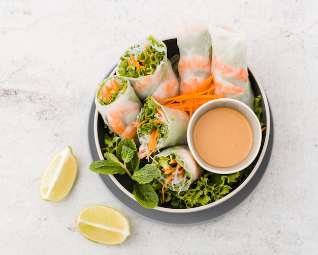 Top view of bowl of shrimp rolls with sauce and lemon
