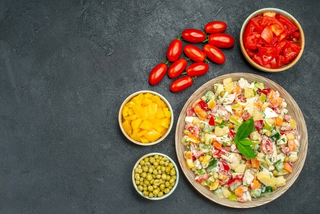 Top view of bowl of vegetable salad with vegetables on dark grey table