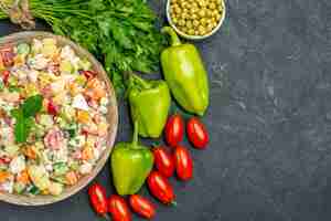 Free photo top view of bowl of vegetable salad with vegetables on side with free space for your text on dark grey background