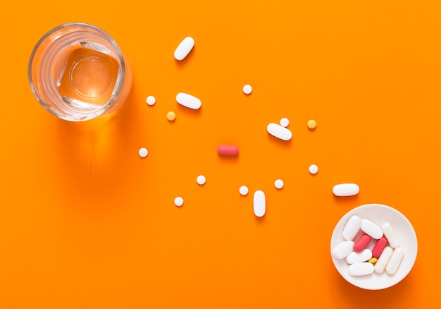 Top view of bowl with pills and glass of water