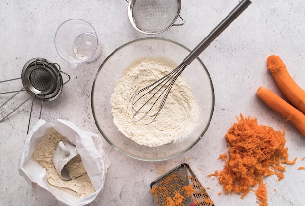 Free photo top view bowl with whisk surrounded by carrots