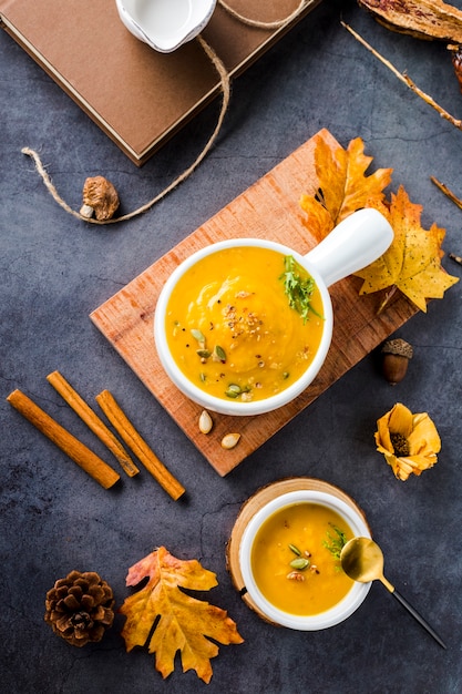 Top view bowls of butternut squash soups on wooden board