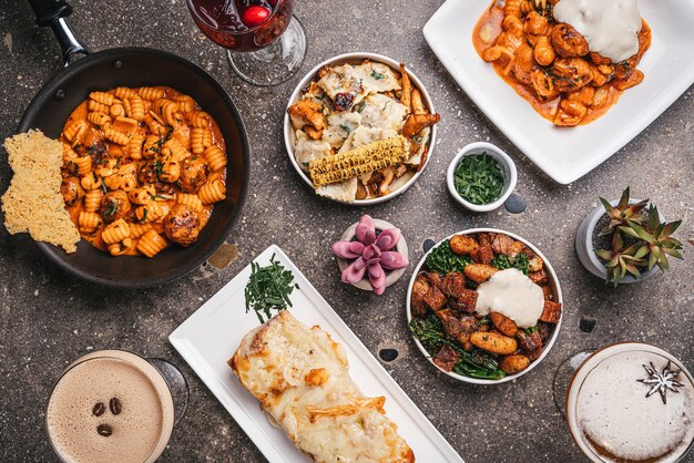 Top view of bowls of cooked pasta with salads and fried vegetables on the table