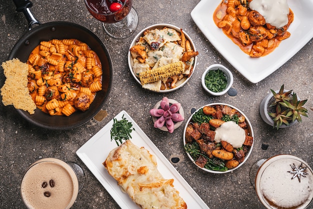 Top view of bowls of cooked pasta with salads and fried vegetables on the table