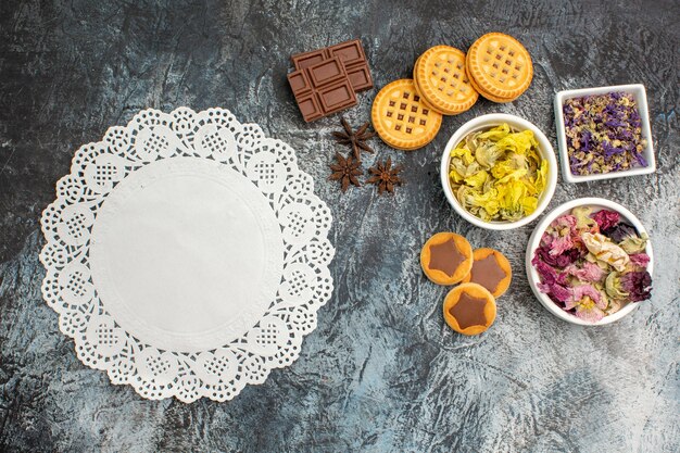 회색 배경에 흰색 레이스와 초콜릿과 쿠키와 마른 꽃 그릇의 상위 뷰