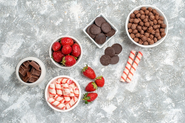 사탕 딸기 초콜릿 시리얼 사탕과 회색 흰색 바닥에 일부 딸기 사탕 초콜릿 상위 뷰 그릇