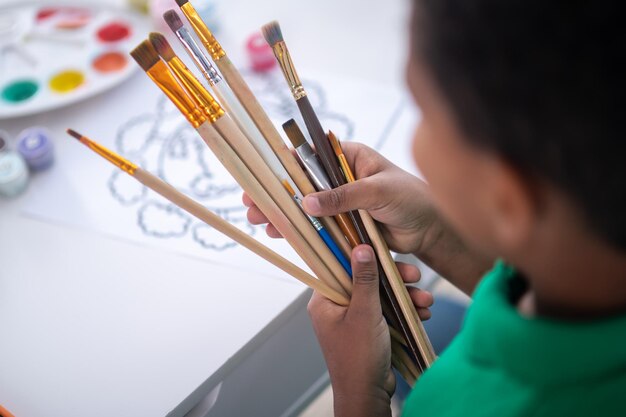 Top view of boy hands holding paintbrushes