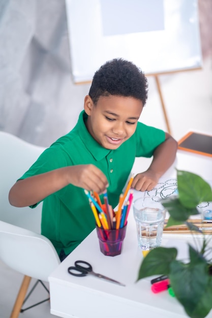 Top view of boy taking out pencil from glass