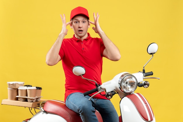 Foto gratuita vista dall'alto di brainstorming giovane ragazzo che indossa camicia rossa e cappello consegna ordini su sfondo giallo