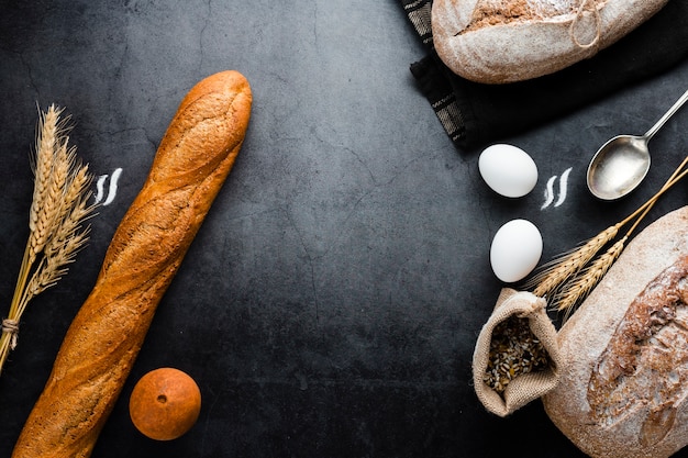 Top view of bread and ingredients on black background