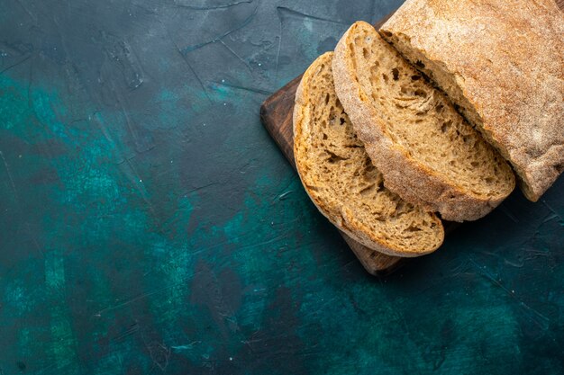 Вид сверху хлебцы, вкусные испеченные и нарезанные на темно-синем столе.