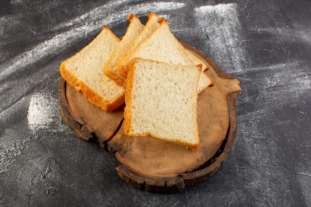 Вид сверху буханки белого хлеба на коричневом деревянном столе и сером фоне булочки из теста