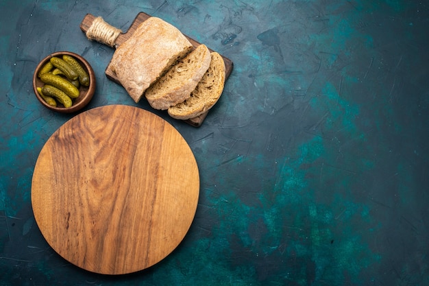 Top view bread loafs with pickles on dark-blue desk.