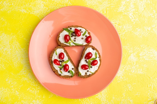 Top view of bread slices with sour-cream inside peach plate on the yellow surface