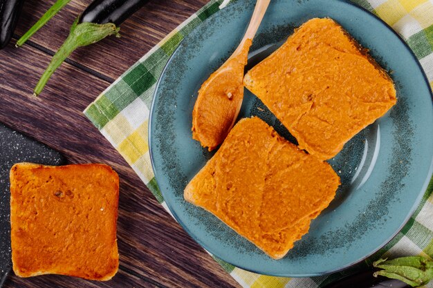 Top view of bread toasts with eggplant caviar on a plate with wooden spoon