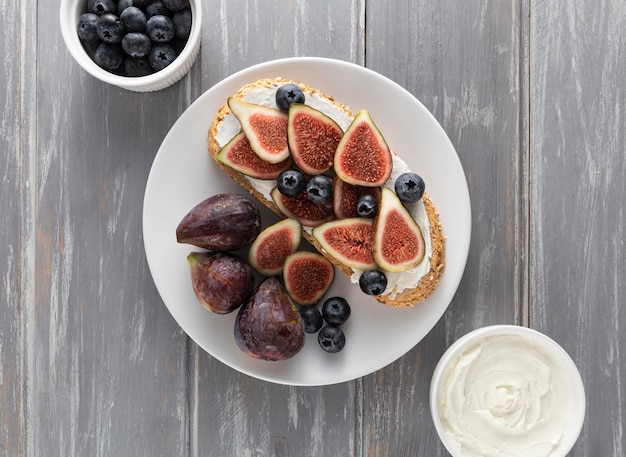 Foto gratuita vista dall'alto pane con crema di formaggio e fichi sul piatto