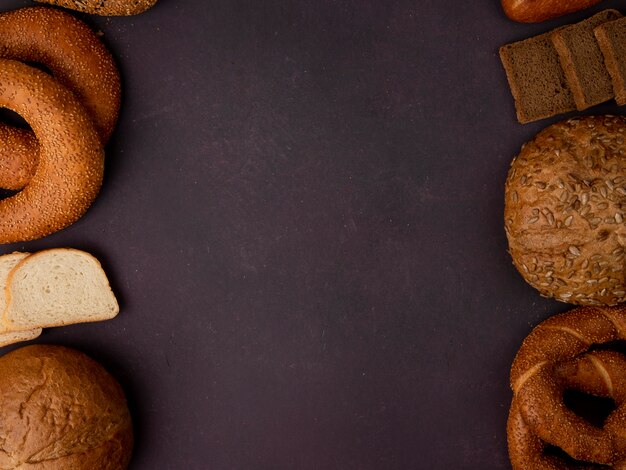 Top view of breads as bagel classic and seeded cob bagel white and rye bread slices on maroon background with copy space