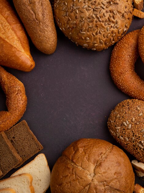 Top view of breads as baguette cob bagel black and white ones on maroon background with copy space