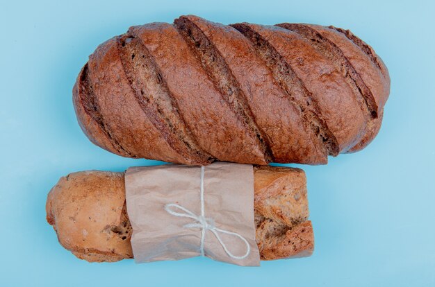 Top view of breads as crispy baguette and black bread on blue table