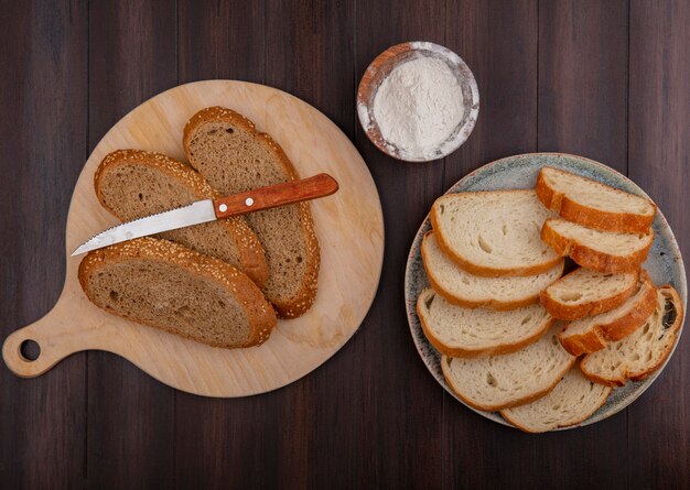 まな板の上にナイフで、木製の背景にプレートと小麦粉でスライスしたシードブラウンコブバゲットクロワッサンとしてパンの上面図
