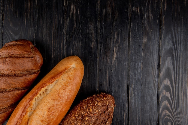 Top view of breads as vietnamese and black seeded baguette and black bread on wooden background with copy space