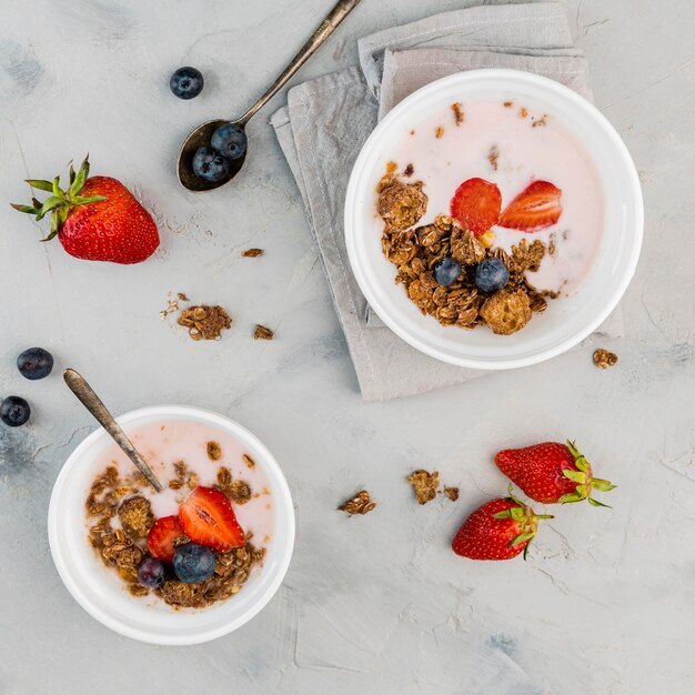Top view breakfast bowls with granola and milk