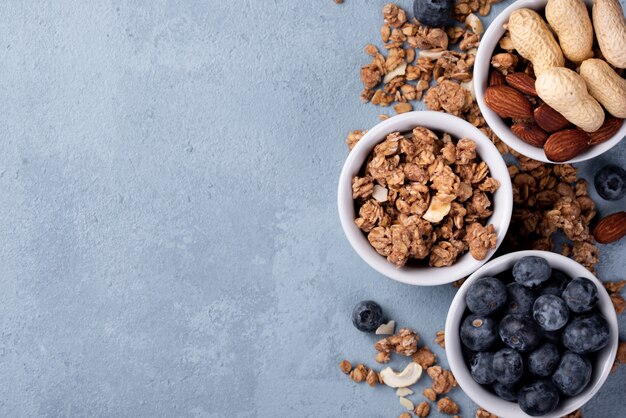 Top view of breakfast cereal in bowl with assortment of nuts and blueberries