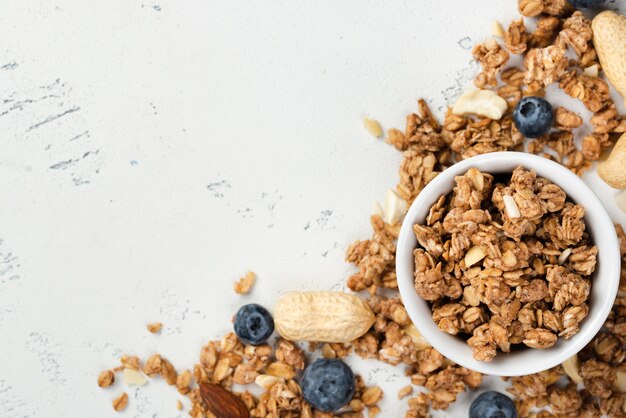 Top view of breakfast cereal in bowl with nuts and blueberries