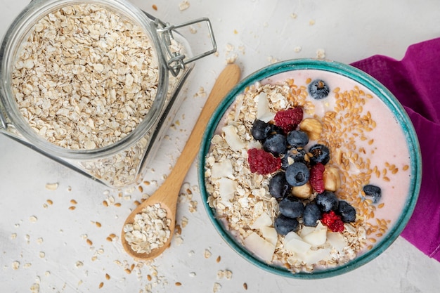 Top view of breakfast cereals in bowl with spoon and fruits