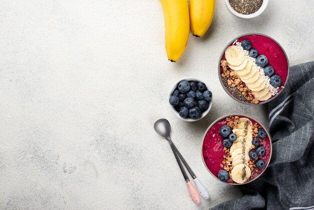 Top view of breakfast desserts in bowls with bananas and spoons