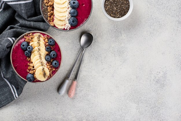 Top view of breakfast desserts in bowls with fruits and copy space