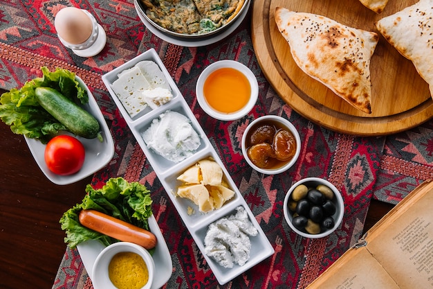 Foto gratuita vista dall'alto marmellata colazione miele burro formaggi ricotta salsicce verdure uovo e pane all'aria