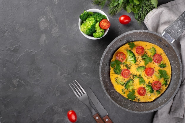 Top view of breakfast omelette in pan with tomatoes and broccoli