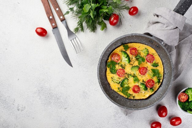 Top view of breakfast omelette in pan with tomatoes and copy space