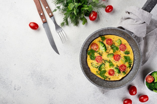 Top view of breakfast omelette in pan with tomatoes and copy space