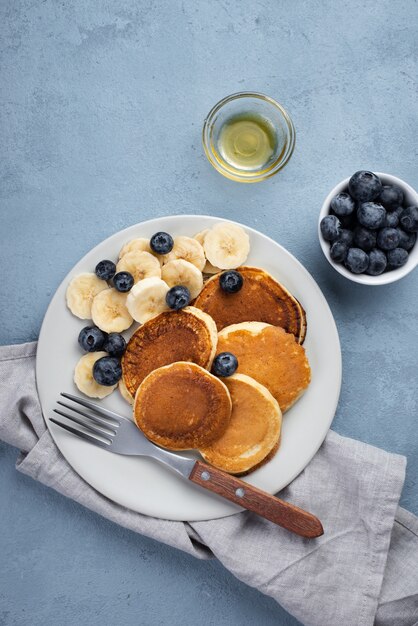 Top view of breakfast pancakes on plate with blueberries and banana slices