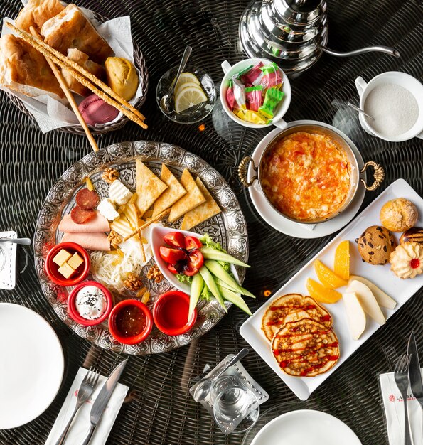 Top view of breakfast table with egg dish jams cheese sausages pancakes