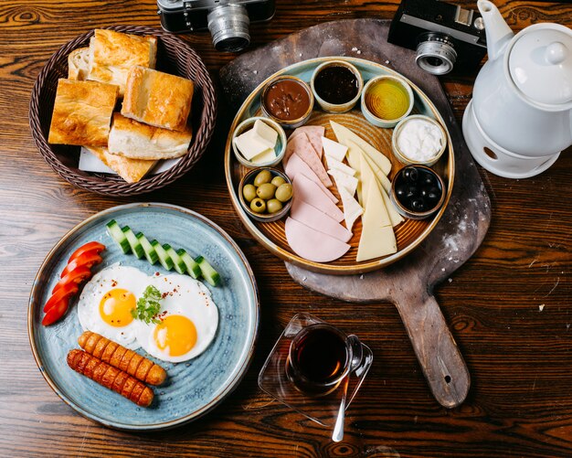 Top view of breakfast table with fried egg and sausages fresh vegetables cheese and ham