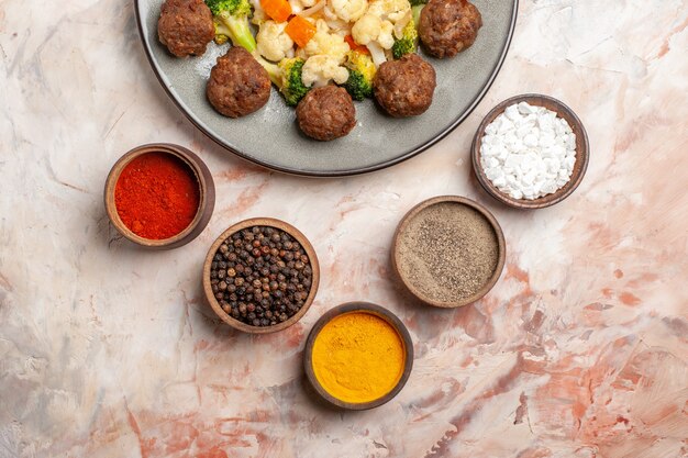 누드 배경 음식 사진에 다채로운 향신료와 함께 접시 그릇에 상위 뷰 브로콜리와 콜리플라워 샐러드와 미트볼