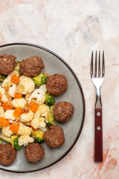 Foto gratuita vista dall'alto insalata di broccoli e cavolfiore e polpetta sul piatto una forchetta su sfondo nudo isolato