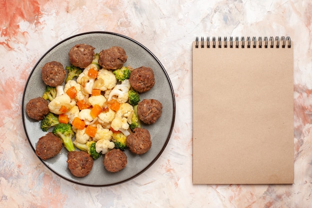 Free photo top view broccoli and cauliflower salad and meatball on plate a notebook on nude isolated background