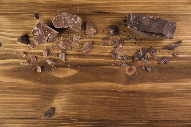 Бесплатное фото Вид сверху сломанный шоколад на деревянном фоне