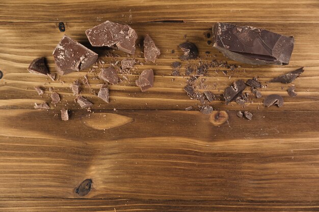 Top view broken chocolate on wooden background