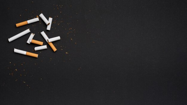 Top view of broken cigarette with tobacco on black backdrop