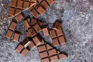 Free photo top view broken dark chocolate on grunge table